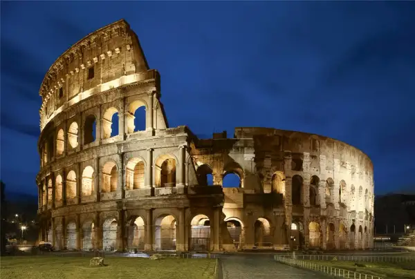El Coliseo Romano, un ícono de la arquitectura antigua, iluminado bajo el cielo nocturno.