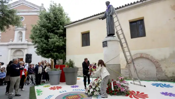 Ofrenda floral a San Pedro Regalado. Un hombre y una mujer colocan flores ante la estatua.