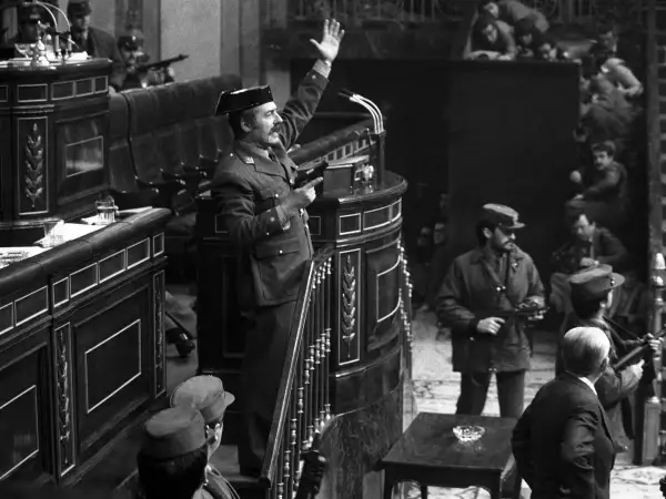 Un militar con pistola en mano, saludando, en el Congreso durante el golpe de estado de Tejero. Soldados armados observan.