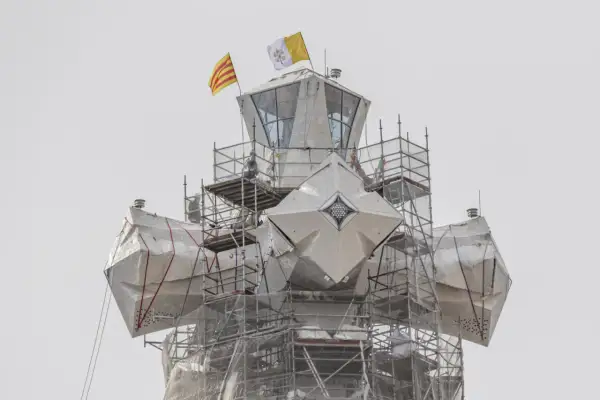 La torre de Jesús de la Sagrada Familia, cubierta con lonas y rodeada de andamios, ondea las banderas de Cataluña y el Vaticano.
