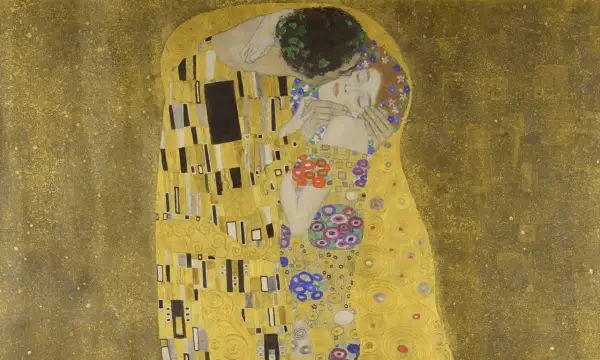 El beso de Gustav Klimt: una pareja abrazada en un campo dorado, ella con flores en el pelo, él con una corona de hojas.