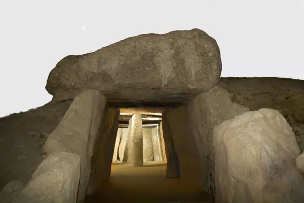 Entrada al dolmen de Menga, un túnel megalítico con pilares de piedra y una gran losa cubriendo la entrada.