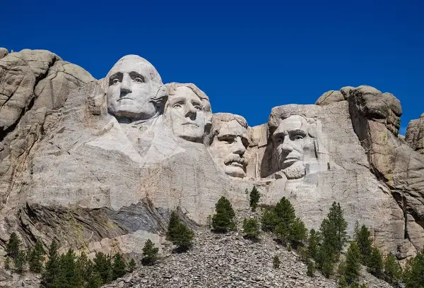 Las caras de cuatro presidentes de EE.UU. talladas en el **Monte Rushmore**, bajo un cielo azul intenso.