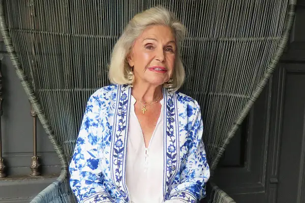 Beatriz de Orleans Borbón, con su elegante chaqueta floreada, sonríe sentada en un sillón de mimbre.