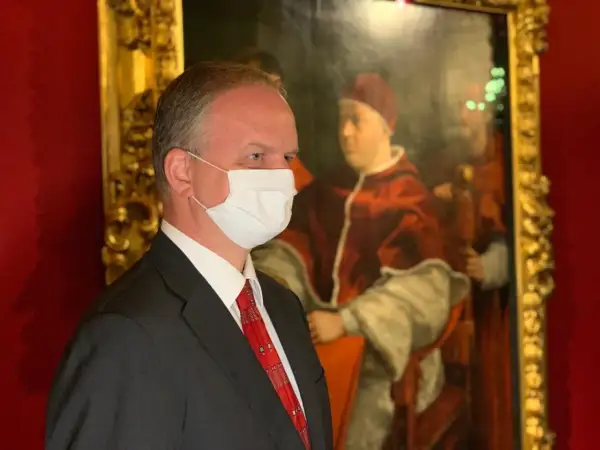 Hombre con mascarilla frente a un retrato del papa León X.