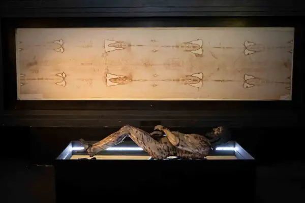 La sabana santa de Turín, con la imagen de un hombre crucificado, se exhibe junto a una figura que representa su cuerpo.