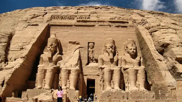 Gigantescas estatuas de Ramsés II flanquean la entrada del templo de Abu Simbel, Egipto. Un pequeño grupo de turistas admira la magnificencia de esta maravilla antigua.