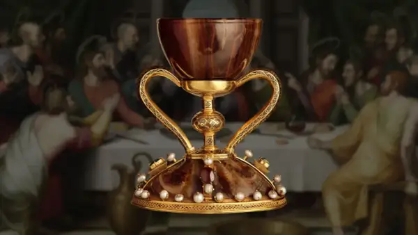 El cáliz dorado, adornado con perlas y gemas, evoca la búsqueda del santo grial donde está. Detrás, la Última Cena.