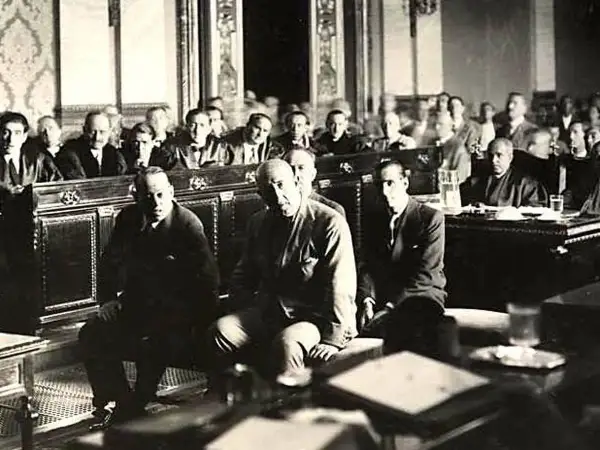 Hombres sentados en una sala, uno de ellos es José Sanjurjo y Prieto, en un evento histórico.